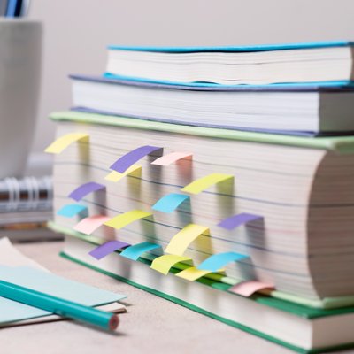 Books on a study table with notes and bookmarks, along with stationery items