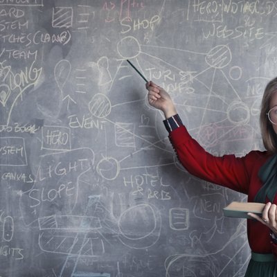 a young teacher near the blackboard explain difference between language dialects. The Langly logo is visible in the bottom left corner.