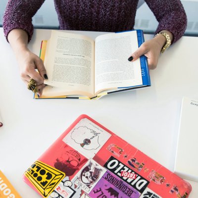 A person sitting at a table studying something in a book, with a closed laptop in front of. Langly logo in the bottom left corner